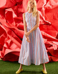Woman in a striped dress standing in front of a large red flower-like structure.