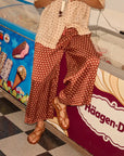 Person wearing a patterned outfit standing in front of an ice cream freezer with 'Haagen-Dazs' branding. close up on pant