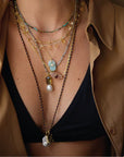 Person wearing a beige shirt and black bikini top with layered necklaces.