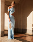 Woman in a light blue off-shoulder dress with Florence Chainmail Bag standing in a sunlit architectural setting.