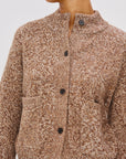 Close-up of a brown textured cardigan with black buttons on a light gray background