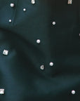 Close-up of black fabric with small decorative stones and pearls.