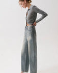 model wearing a rhinestone blue jean with a long sleeve grey top on a white background, side view