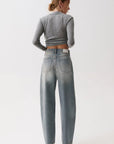model wearing a rhinestone blue jean with a long sleeve grey top on a white background, back view