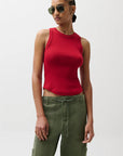 Woman wearing a red sleeveless top and green pants against a white background