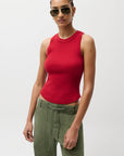 Person wearing a red sleeveless top and green pants on a white background