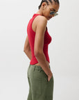 Woman wearing a red sleeveless top and green cargo pants against a white background