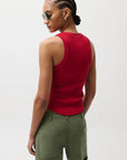 Woman wearing a red sleeveless top and green pants against a white background