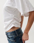 Person wearing a white oversized shirt and blue jeans on a plain background