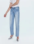 Person wearing light blue jeans with studs and a white shirt on a white background