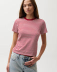 Woman wearing a red and white striped shirt with blue jeans on a plain background