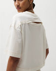 Woman wearing a light-colored top with cut-out design on a white background