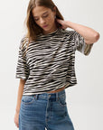 Woman wearing a zebra print crop top and blue jeans on a white background