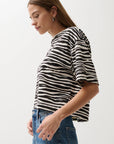 Woman wearing a black and white zebra-striped shirt against a plain background