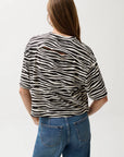 Person wearing a zebra-striped shirt and blue jeans on a white background
