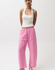 Woman wearing a white top and pink pants on a white background