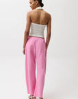 Woman wearing a white strapless top and pink pants on a white background