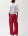 Person wearing a white top and red pants on a white background