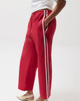 Red pants with white stripes worn by a person on a white background