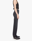 Woman wearing black tank top and dark jeans standing against a white background