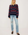 stripe polo top worn by a model with jeans on a grey background