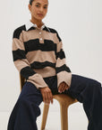 Person wearing a striped sweater sitting on a chair against a white background