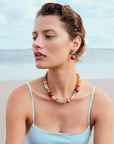 Woman wearing Souvenir Necklace in Sienna and earrings on a beach