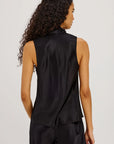 Woman wearing a black sleeveless top and pants on a plain background