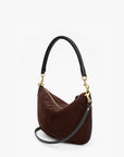 A dark brown suede crescent-shaped shoulder bag with a black leather handle and a black braided detail on the side, accented by gold-tone hardware.