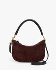 A dark burgundy suede crescent-shaped shoulder bag with black leather trim, gold-tone hardware, and a black shoulder strap, shown against a plain white background.