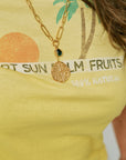 Gold necklace with a pendant on a yellow shirt with text