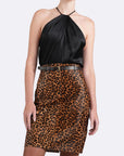 Woman wearing a black halter top and leopard print skirt on a white background
