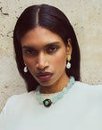 Woman wearing a necklace and earrings against a neutral background