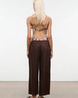 Person wearing a patterned top and brown wide-leg pants against a white background