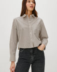 Woman wearing a striped shirt and black jeans against a white background front view