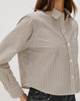 Woman wearing a striped shirt with a neutral background side view
