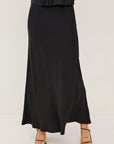 Person wearing a black dress with a plain background