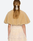 A model wearing a tan fuzzy faux-fur cape with a tie-neck detail, layered over a cream lace dress, against a light gray background, back view