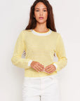 Woman wearing a yellow textured sweater against a white background