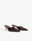 A pair of dark brown patent leather pointed-toe mule heels with slim kitten heels, displayed on a clean white background.