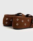 Pair of brown shoes with grommets on a light gray background