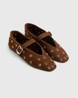 Brown studded shoes with a buckle on a light gray background