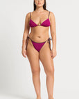 model wearing magenta bikini on white background