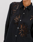 Black shirt with cut-out designs on a white background detail view