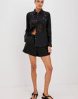 Woman wearing a black outfit with floral patterns on a white background front view