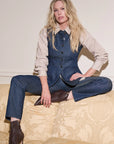 Woman wearing a denim outfit sitting on a patterned couch.