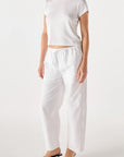 model wearing the simone white pant and a short sleeve with tee with a white background, side