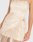 model wearing a cream colored romper with fringe scarf detail