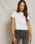 Woman wearing a white t-shirt and gray jeans against a plain background