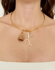 Gold necklace with shell and coral pendant on a person's neck